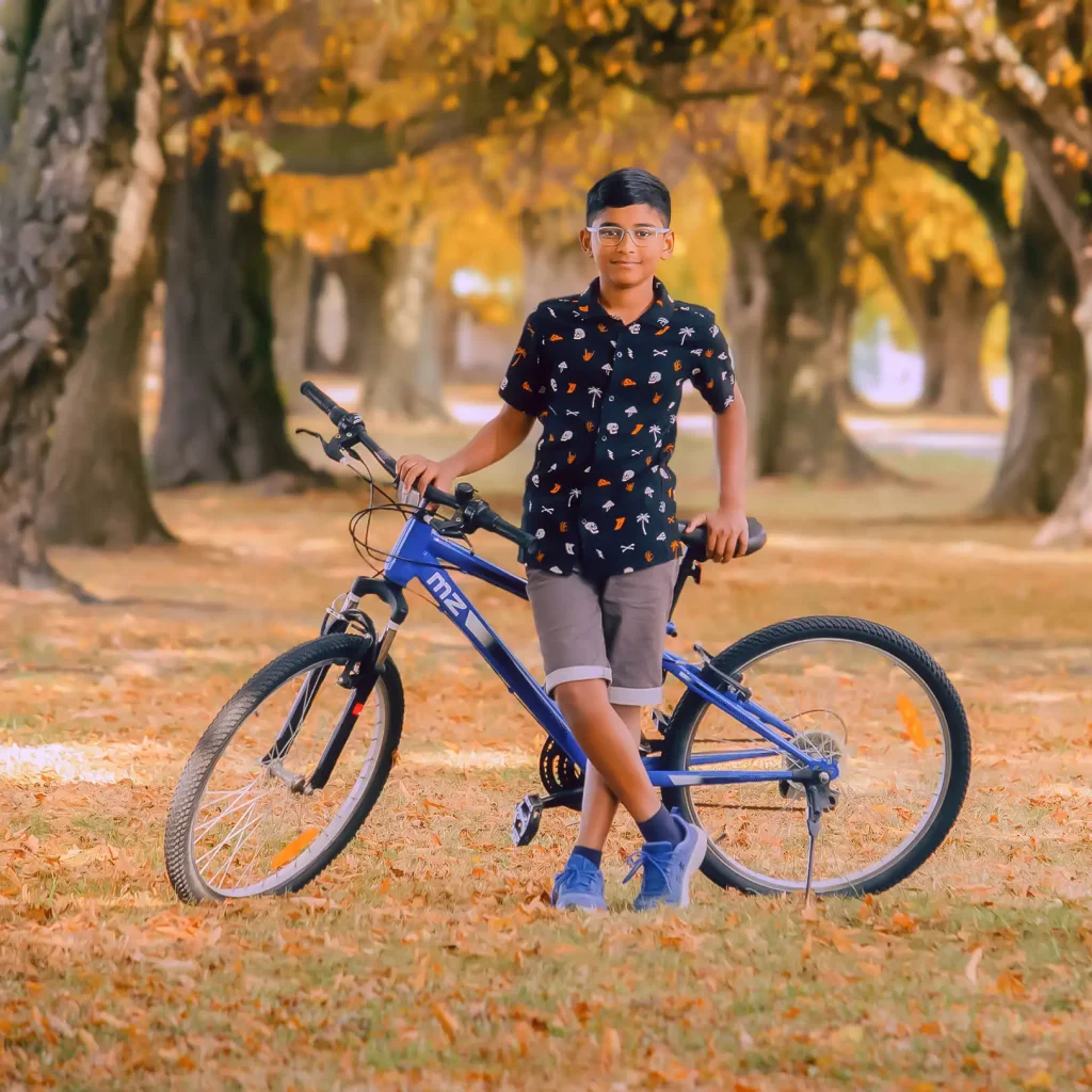 Young boy with bicycle under autumn trees in Christchurch