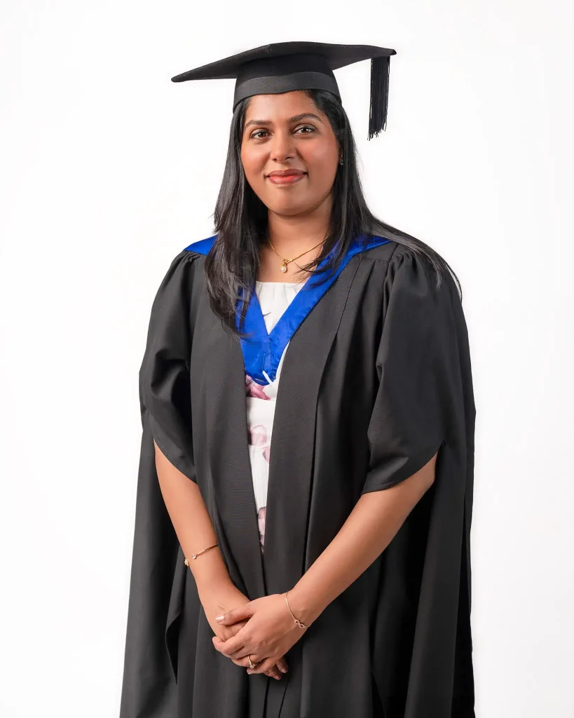 Female graduate in academic gown and cap posing for graduation portrait