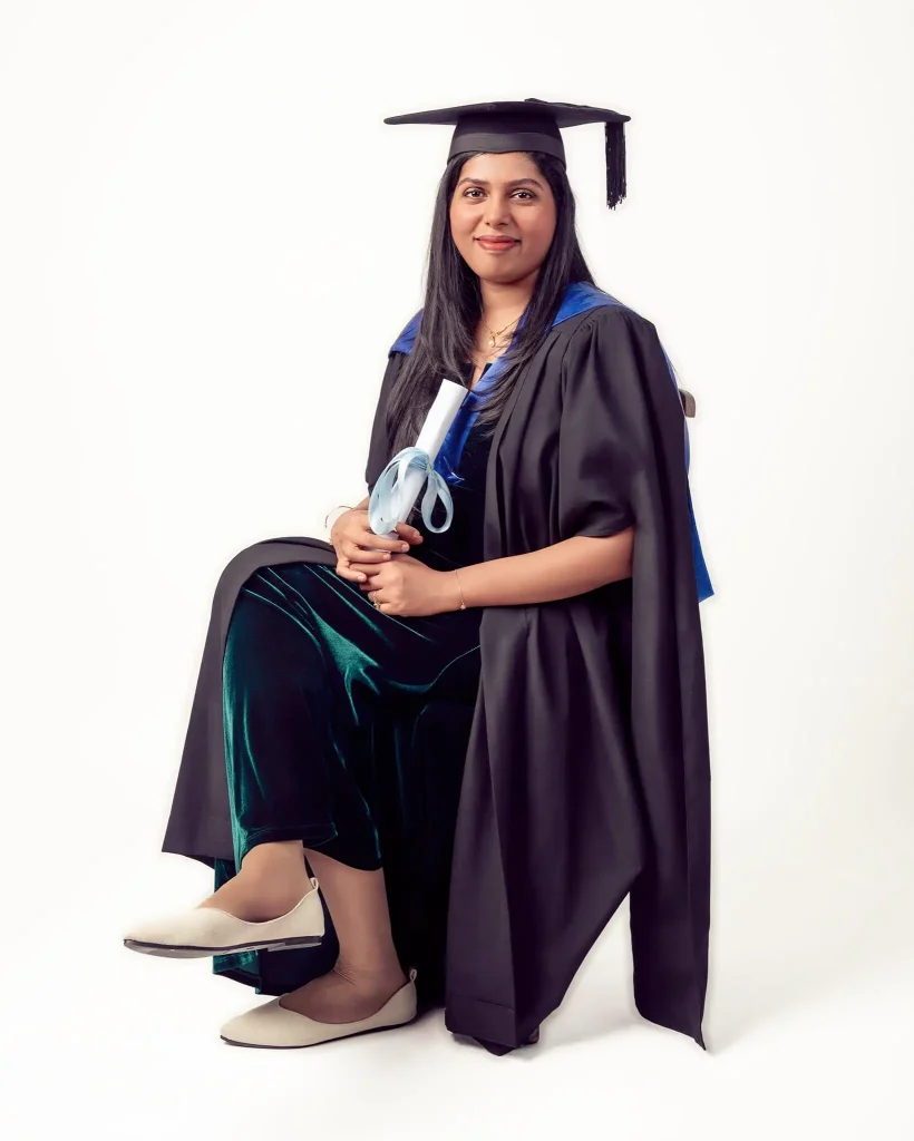 Female graduate in academic gown and cap posing for graduation portrait