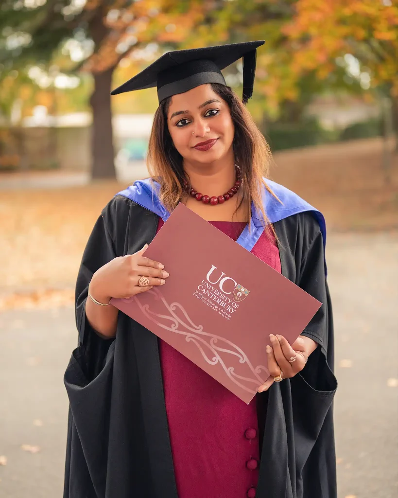 Woman holding graduation certificate outdoors in Christchurch