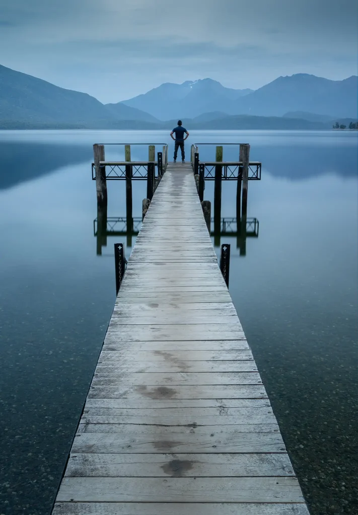 Man standing on pier overlooking Lake Te Anau in New Zealand