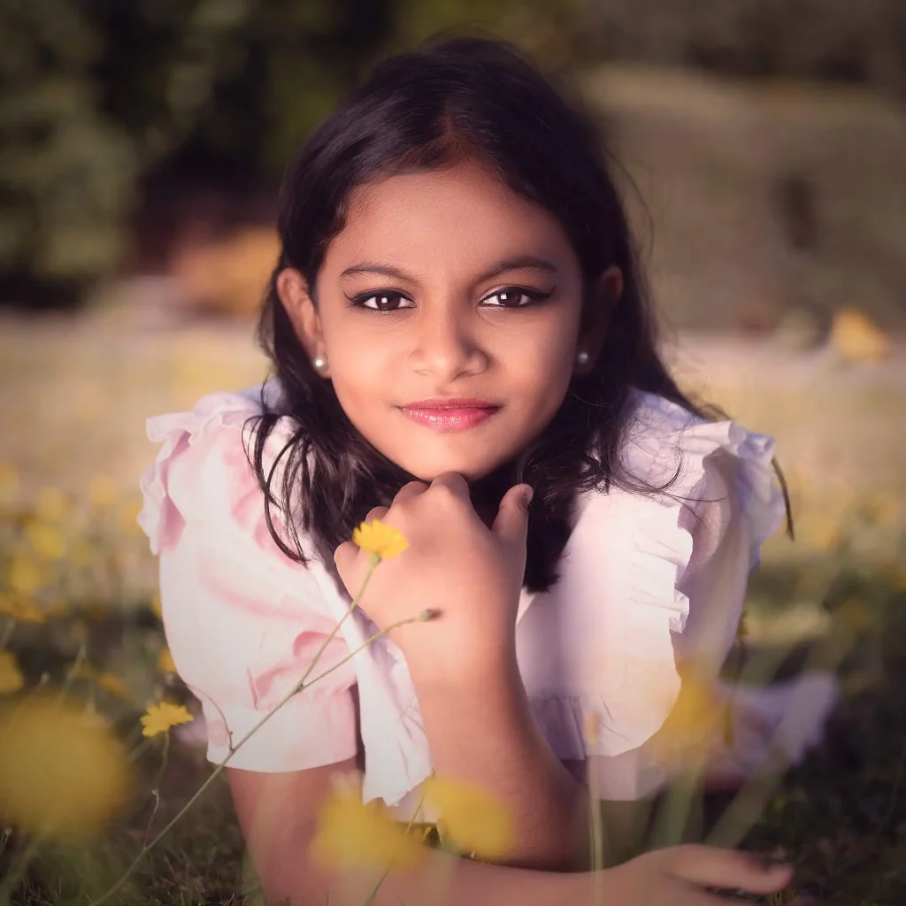 Young girl lying in a field of yellow flowers smiling in soft outdoor light in Christchurch