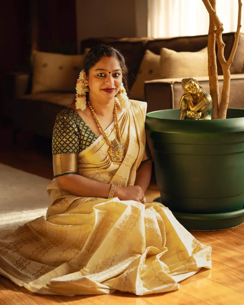 Indian woman in gold saree sitting indoors with soft natural light and a decorative plant in Christchurch