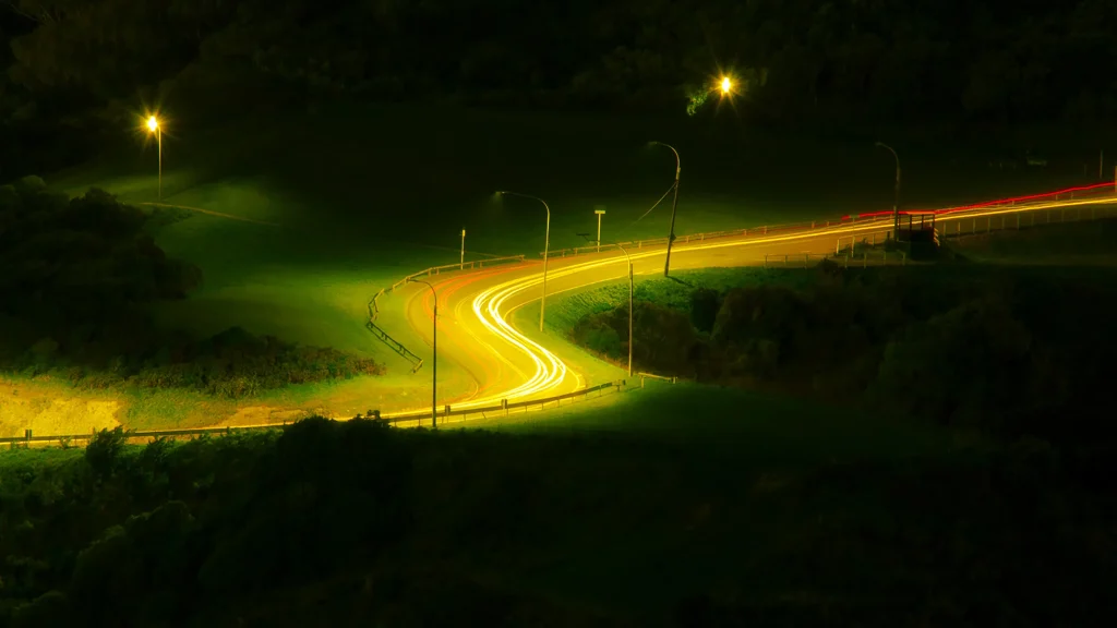 Curving road illuminated by light trails at night captured with long exposure