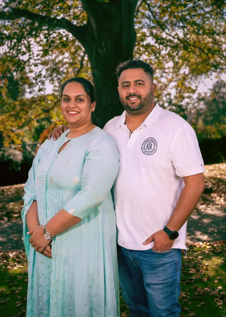 Smiling couple posing outdoors under a tree during autumn in Mona Vale Park