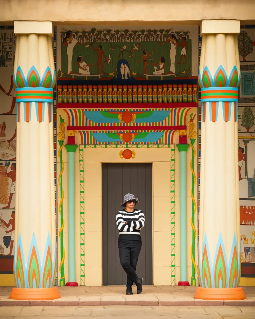 Woman posing in front of colorful Egyptian-style pillars at Hamilton Gardens