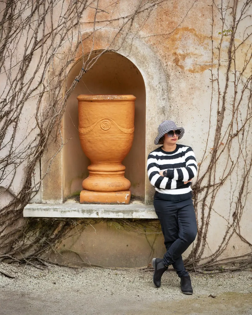 Woman leaning beside a large terracotta pot in an arched niche at Hamilton Gardens
