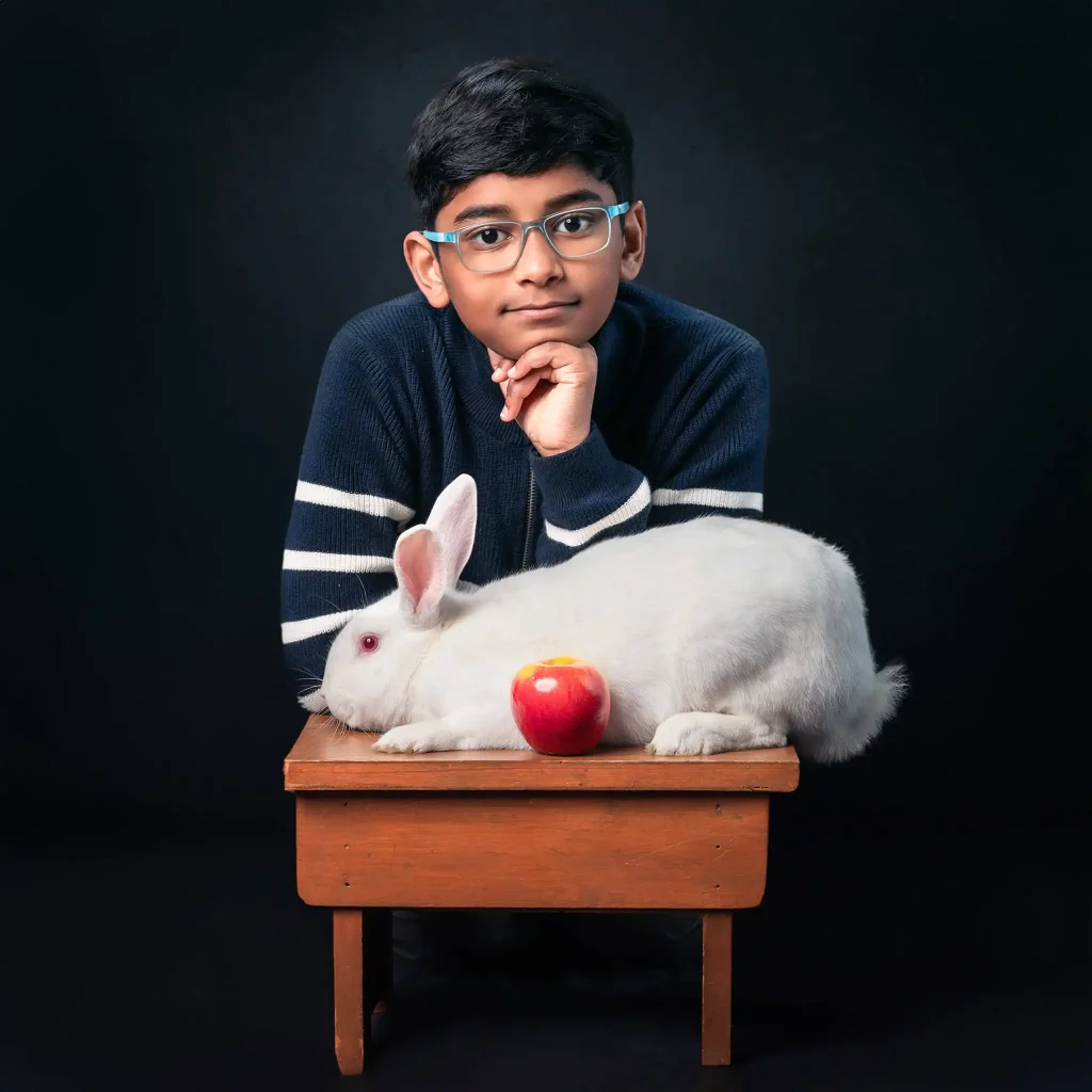 Studio portrait of boy with white rabbit and red apple on wooden table in Christchurch