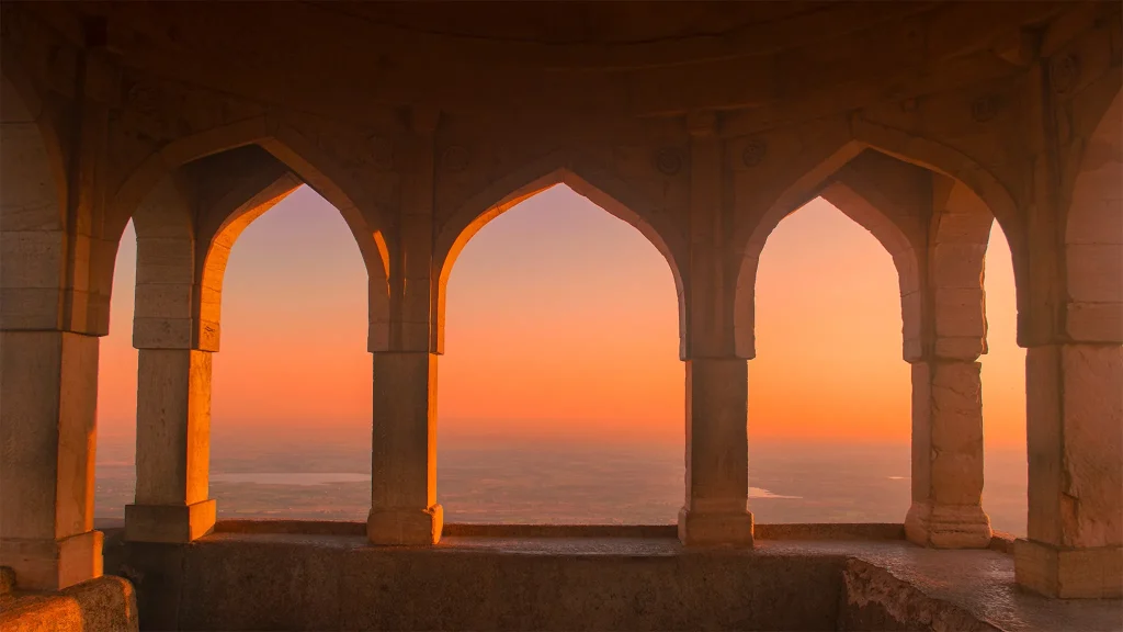 Sunset sky framed by a series of stone arches overlooking the horizon at Rani Roopmati Palace