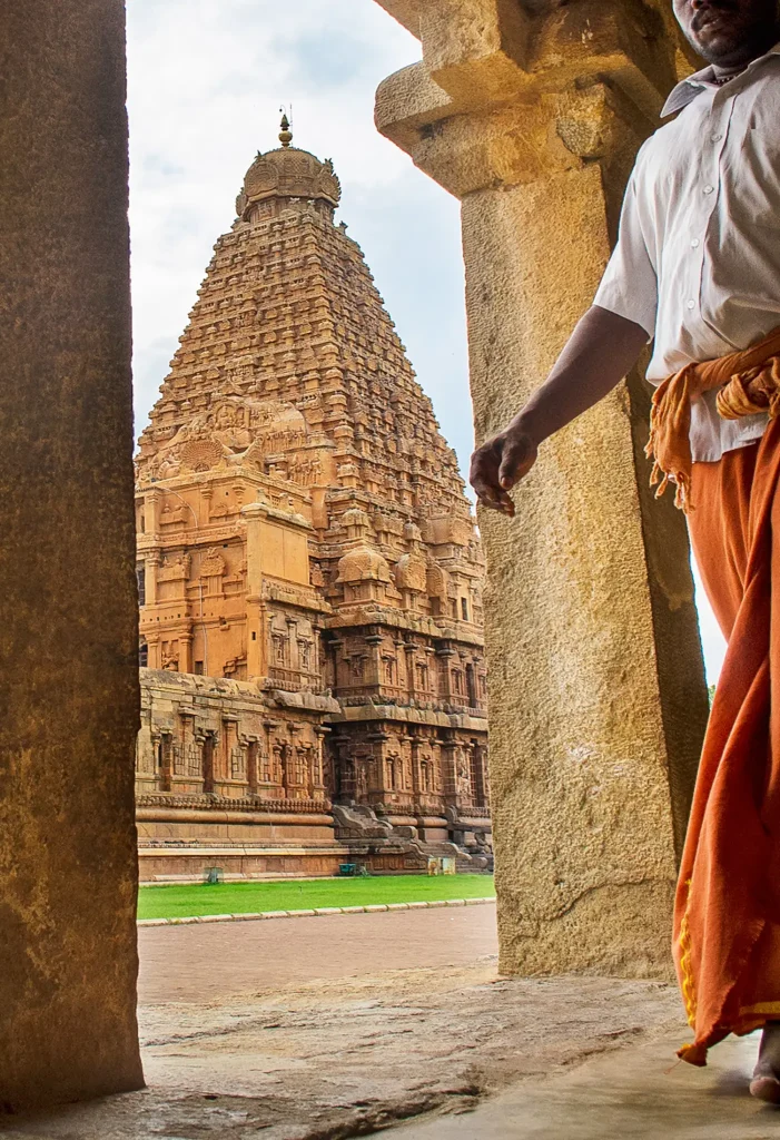 Thanjavur temple tower seen through a stone archway with a visitor in traditional attire