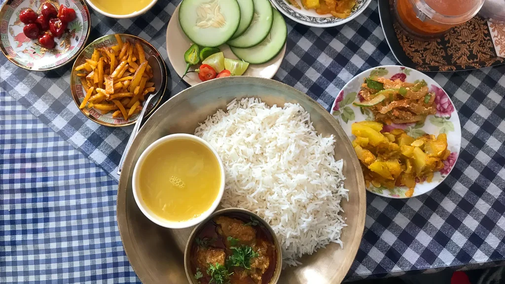 Top-down view of a traditional Indian Sikkim meal with rice, curry, and side dishes on a checkered cloth