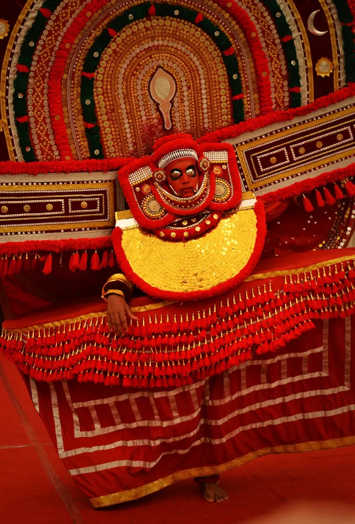 Vibrant portrait of a traditional Theyyam-style ritual performer in elaborate red and yellow costume