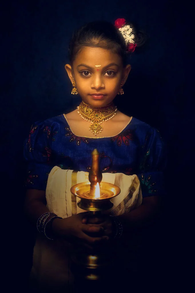 Young girl in traditional attire holding a brass oil lamp during portrait session in Christchurch